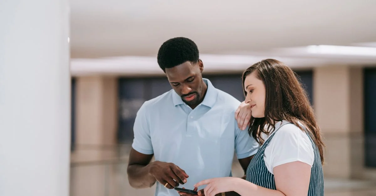 Um casal em ambiente interno discutindo algo em um smartphone com expressões focadas. Contexto: Chatbot ou automação no WhatsApp: diferenças e quando usar cada um