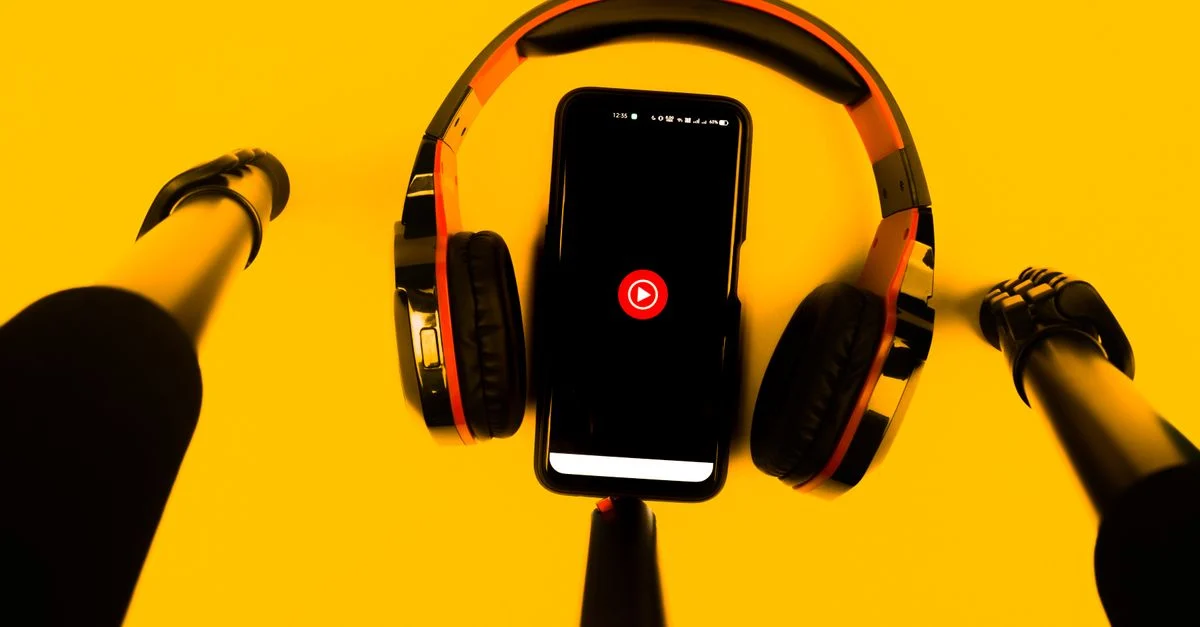 Um smartphone com fones de ouvido sem fio e microfone contra um fundo amarelo vibrante. Contexto: Como escolher afiliados no TikTok Shop para vender mais