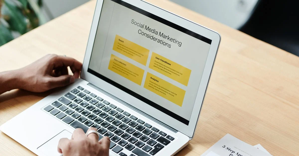 Uma pessoa usando um laptop para revisar estratégias de marketing em mídias sociais em casa. Contexto: Geração de demanda x captura de demanda: qual é a diferença?