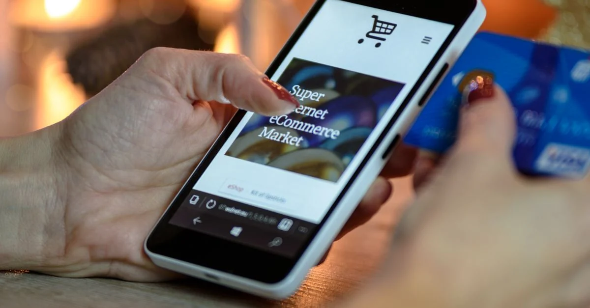 Mulher usando smartphone para compras online com cartão de crédito na mão, iluminação festiva ao fundo. Contexto: Influenciadores no TikTok: como escolher creators para marcas
