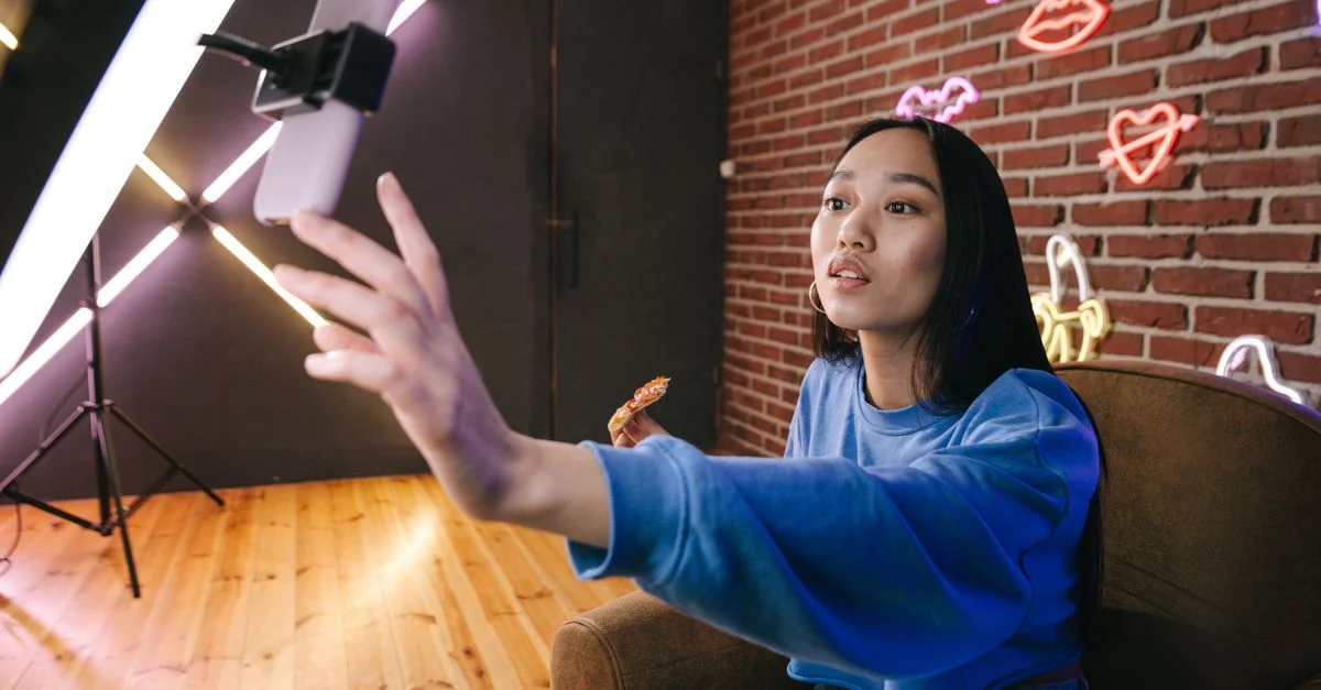 Mulher asiática cria conteúdo para live stream em um ambiente estiloso iluminado por neon. Contexto: Live Shopping no TikTok Shop: como planejar uma live de vendas