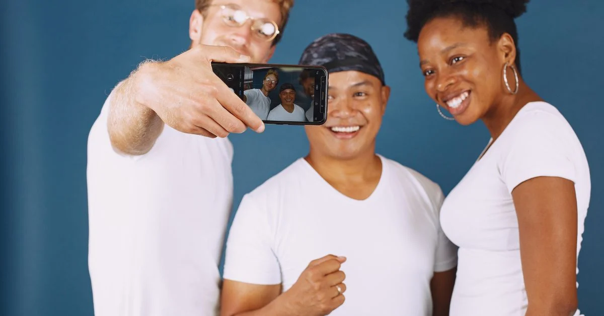 Um grupo diverso de amigos sorrindo e tirando uma selfie dentro de casa. Contexto: Microinfluenciadores: quantos seguidores têm e quando usar